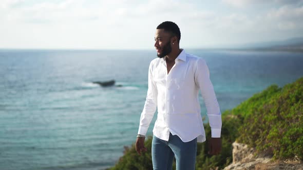 Handsome African American Gay Man Walking at Sunset on Mediterranean Sea Coast Stretching Hands
