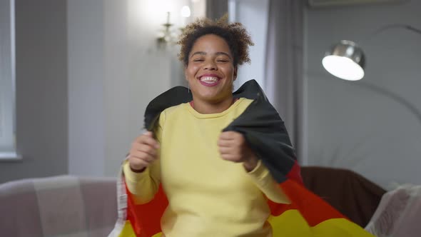 Happy African American Woman with Toothy Smile Wrapping in German Flag Smiling Looking at Camera