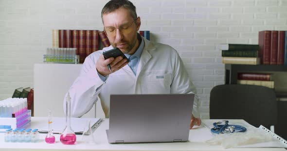 A Middleaged Doctor Records a Voice Message on His Phone