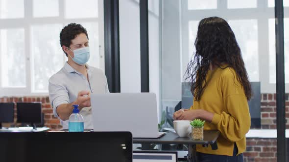 1374507Man and woman wearing face masks working together in office
