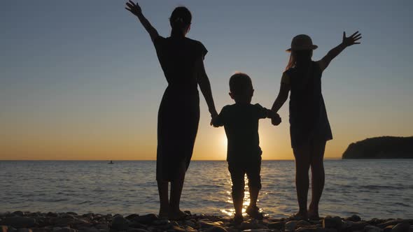 Happy Family Mother with Two Children on Vacation at the Beach. Silhouette Mother with Two Children