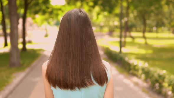 Back View Close Up Woman Talking By Phone Walking on the Street City Park Summer Outdoors