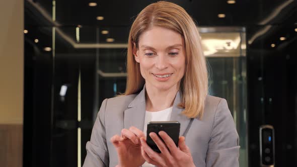 Beautiful Blonde Businesswoman with Mobile Phone in a Modern Business Center