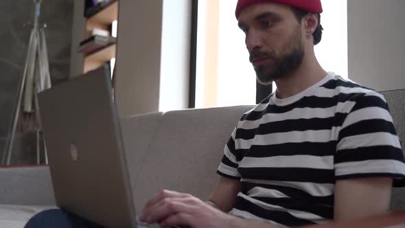 Guy - freelancer sitting on the couch, working on a laptop