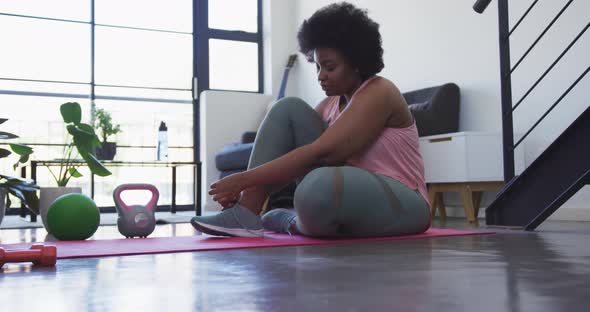 African american female plus size lying on exercise mat working out