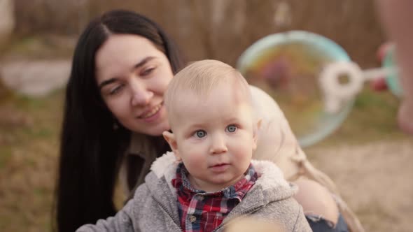 Baby Boy with His Mother Watching Father Blowing Bubbles