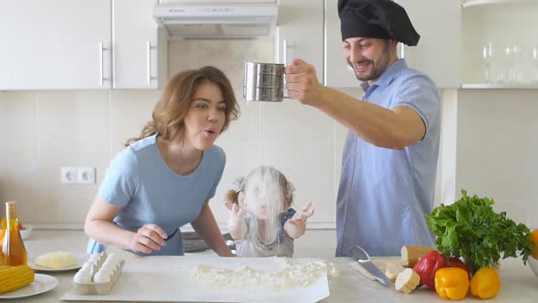 UFA, RUSSIA - APRIL, 2017: Happy Family Is Cooking in The Kitchen. Dad Sifts Flour Slow Motion.