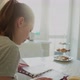 Girl Kitchen Opposite the Window at the Table Leafs Through a Notebook - VideoHive Item for Sale