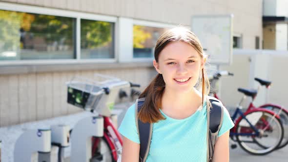 Portrait of happy fifteen-year-old girl by city bikes