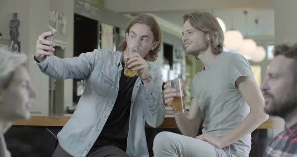 Men taking self photograph with mobile phone while enjoying beer in pub