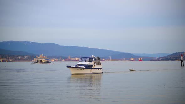 Boat passing slowly in Vancouver Downtown Coal Harbour, pulling another smaller boat