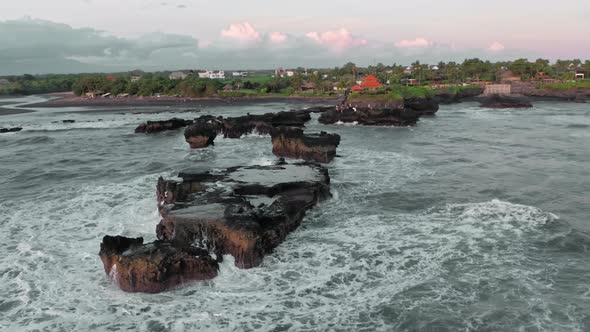 A Beautiful Bird'seye View of Flying Around the Black Rocks on Ocean at the Golden Hour