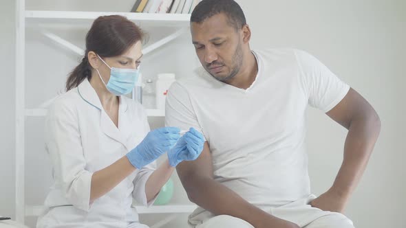 Woman in Face Mask Holding Thermometer and Talking with Ill Man in Hospital. Portrait of Caucasian