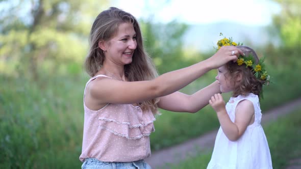 Mom Puts a Wreath of Wildflowers on Her Daughter's Head in Nature