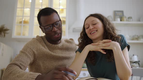 Multinational Couple Discuss Apartment Layout at Table
