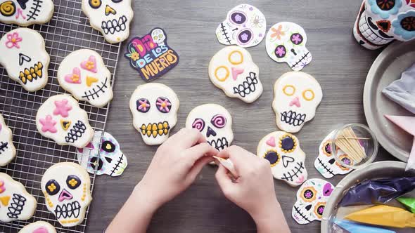 Step by step. Flat lay. Decorating sugar skull cookies with different color royal icing.