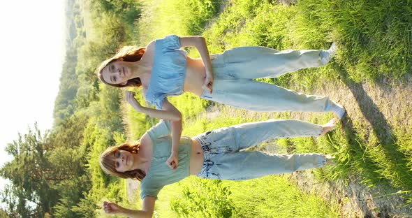 Two Carefree Girls in Stylish Summer Looks Dancing Staging Synchronously