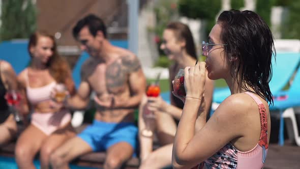 Side View Portrait of Charming Relaxed Young Woman Drinking Cocktail in Slow Motion Smiling Sitting