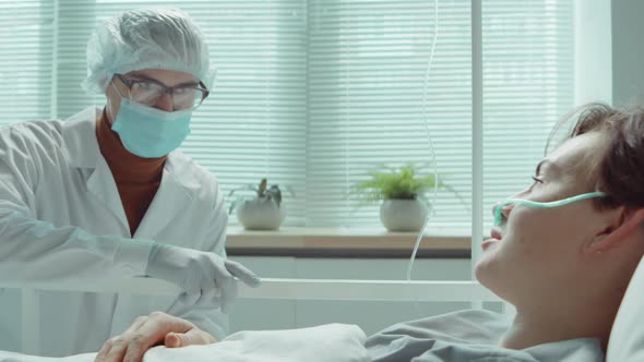 Female Patient Talking with Doctor in Mask in Hospital Ward