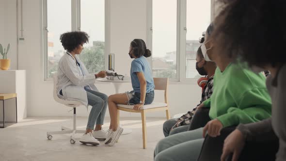 African american doctor is measuring blood pressure and checking pulse child patient.