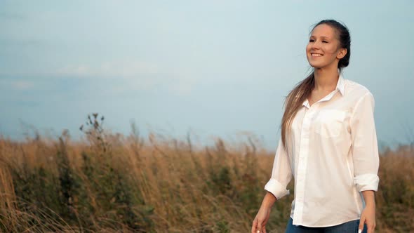 Beautiful Young Lady Walking in Wheat Fields During Sunset