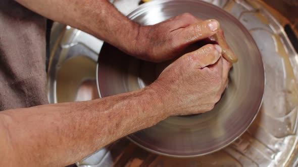 Male Hands of Potter Turn Clay on Potter's Wheel and Give It Desired Shape Top View