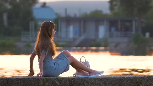 Young Woman in Casual Outfit Relaxing on Lake Side on Warm Evening