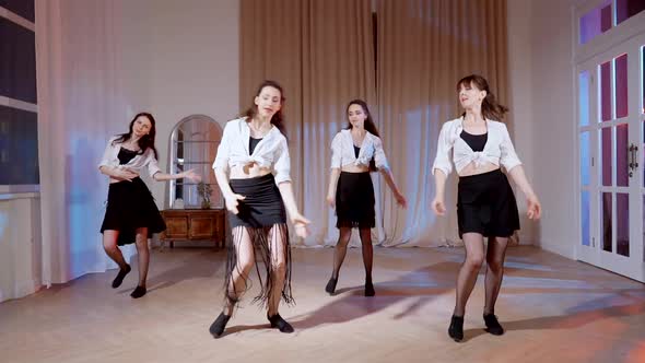 Four Girls in Black Skirts and White Shirts are Dancing Indoors