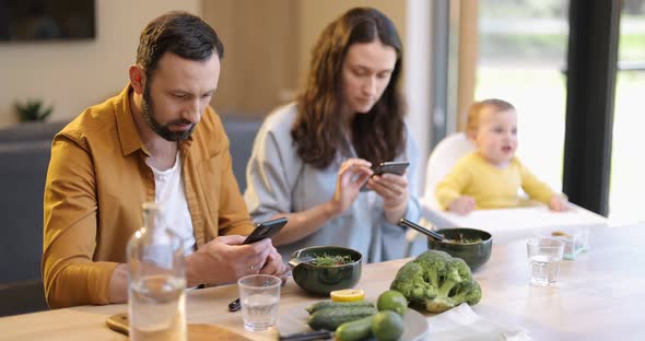 Parents Busy in Their Phones During a Lunch with Their Baby Son