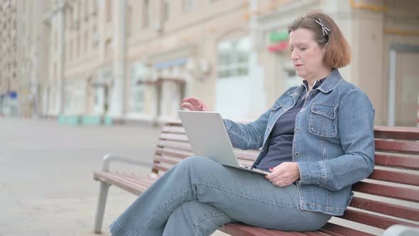 Old Woman Leaving Bench After Closing Laptop