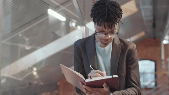 African American Office Worker Taking Notes in Notepad