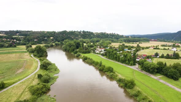 Aerial Drone Shot  a Large River Runs Through a Rural Area with Villages on a Sunny Day