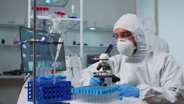 Biologist Doctor Coverall Checking DNA Sample Using Microscope