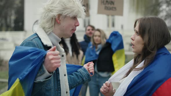 Caucasian woman with Russian flag arguing with caucasian man with Ukrainian flag on street manifesta