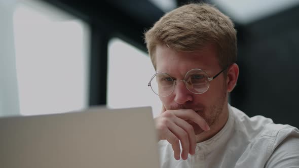 Portrait of a Tired Pensive Man Looking at a Laptop Screen with Glasses