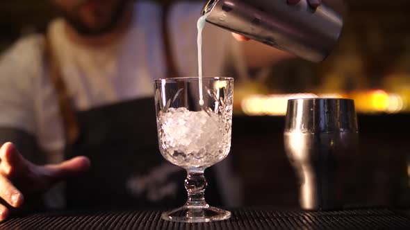 Making an alcoholic cocktail. The bartender pours a cocktail. Cocktail in a glass.