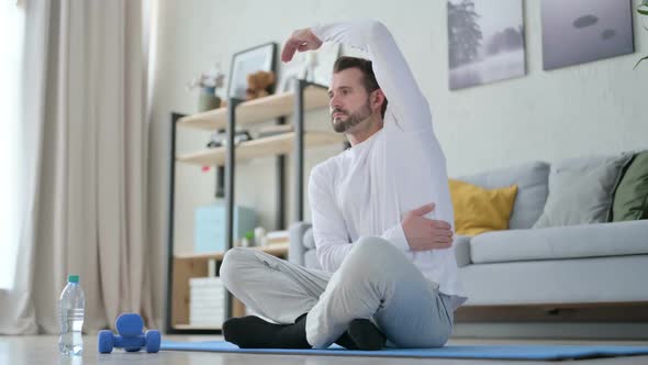 Man Doing Stretches on Yoga Mat at Home