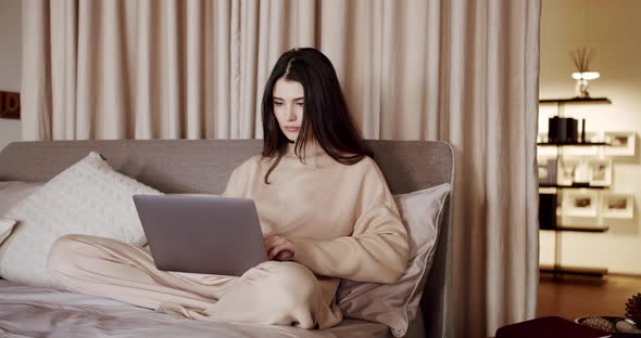 Happy Pretty Female Working From Home on Key Laptop Computer From Bedroom