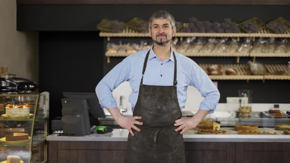 Friendly Male Baker Wipes His Hands on an Apron From Flour and Puts Hands on Hips