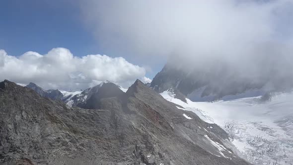 Aerial shot in the swiss alps discovering a wild montain range in the clouds