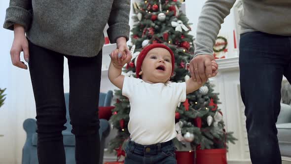 Toddler Trying to Walk while His Parents Holding Him by Both Hands