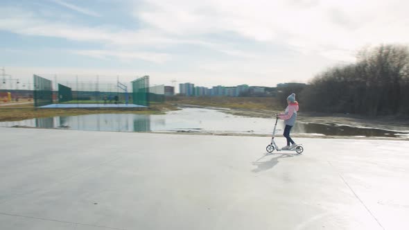 Girl On A Scooter On The Playground