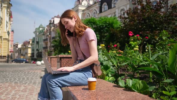 Beautiful Young Woman Tourist with Takeout Coffee in the City Center Using Laptop