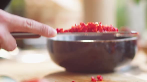 Hands of Male Cook Putting Diced Red Pepper from Cutting Board into Bowl