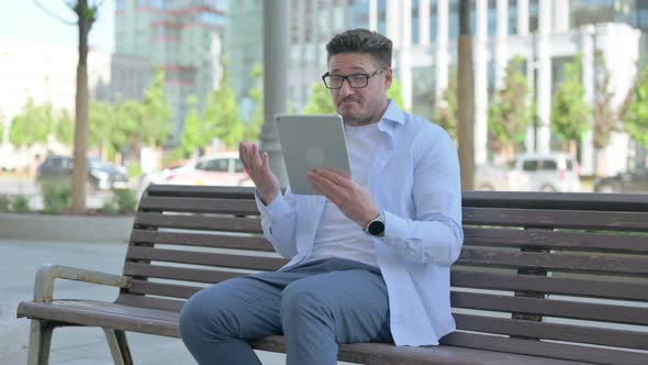 Online Video Chat on Tablet By Man Sitting Outdoor on Bench