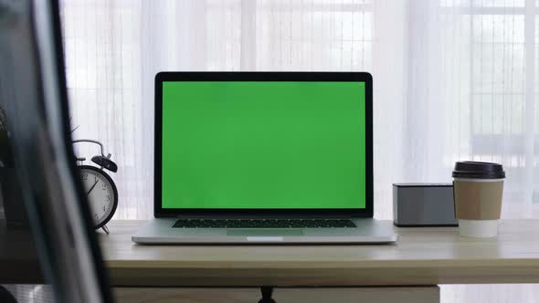 Chroma key green screen of laptop computer set on working space in home office.