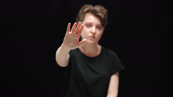 Closeup of Young Female Hand Stretched at Camera with Blurred Caucasian Woman with Serious Facial