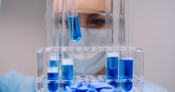 Female Scientist Holding Tubes and Flask with Liquid in Hands alt