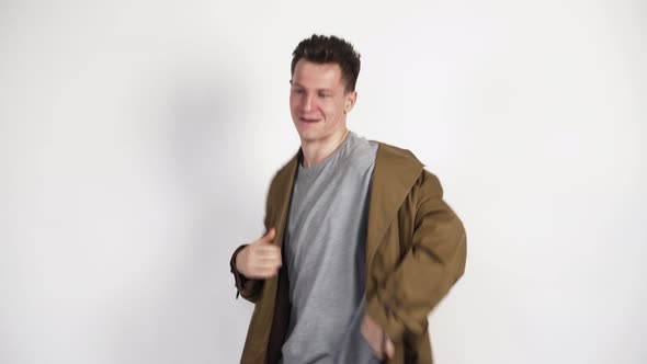 White Guy in a Brown Coat and a Funny Dance on a White Background. In a Good Mood. Positive Video.