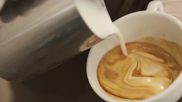 Close Up Barista Hands Pouring Warm Milk in Coffee Cup for Making Latte Art